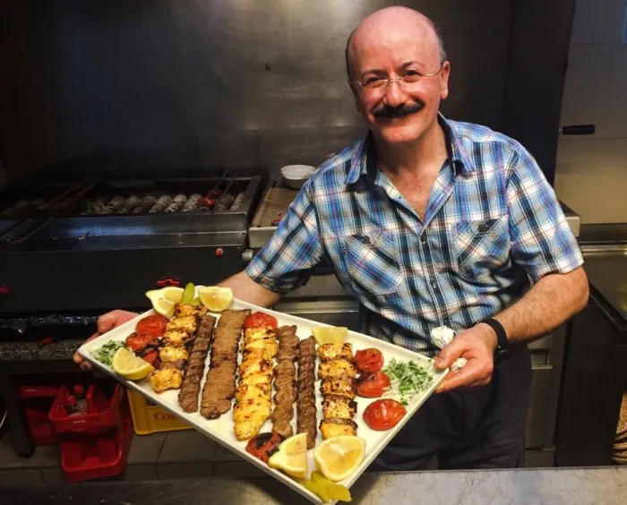 Koch des Safran Restaurants präsentiert eine Grillplatte mit Kebab und Zitrone